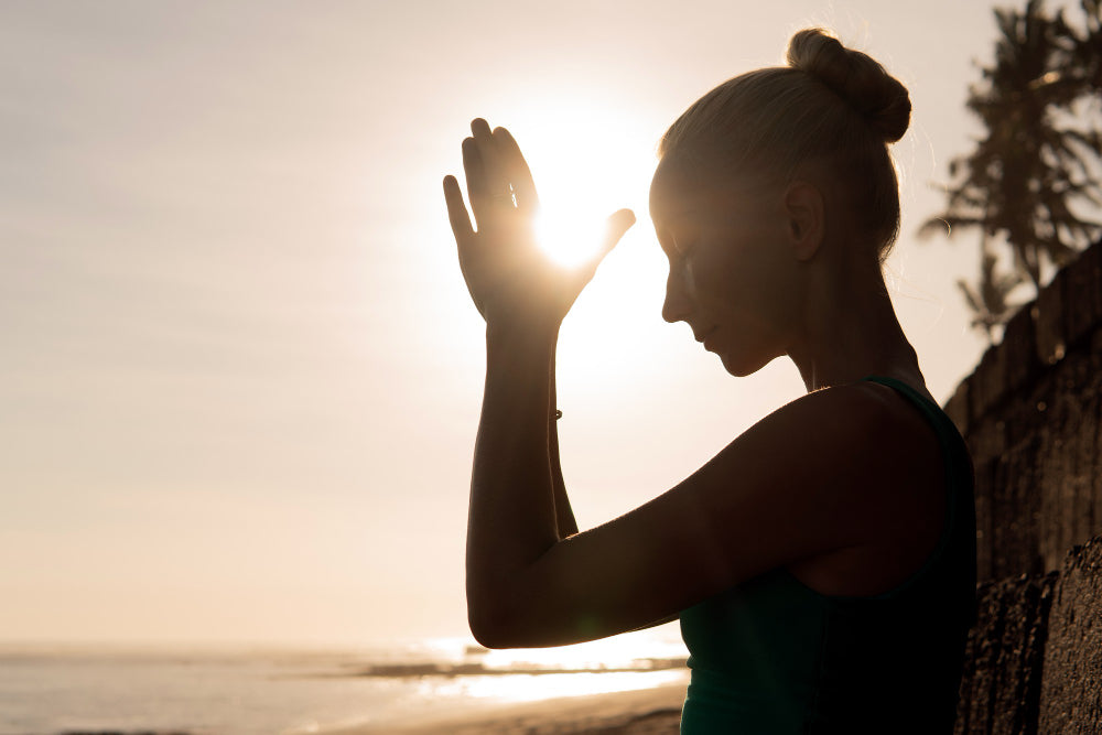 Woman doing yoga in sunset on a beach